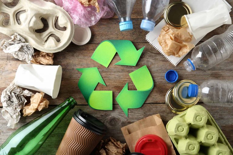 Recycling symbol and different garbage on wooden background, top